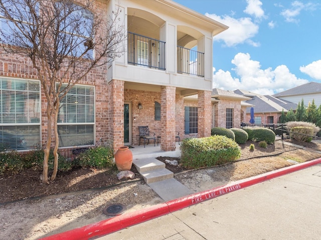 view of front of home with brick siding and a balcony