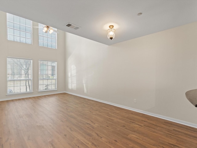 unfurnished room featuring wood finished floors, visible vents, and baseboards