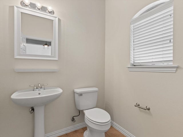 half bathroom featuring baseboards, toilet, and tile patterned flooring