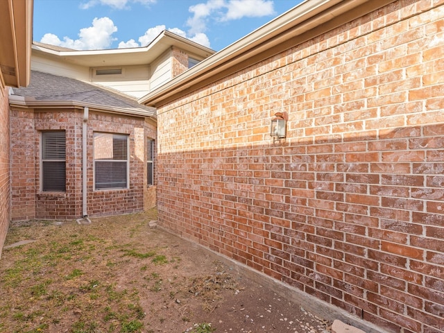 exterior space featuring brick siding and a shingled roof