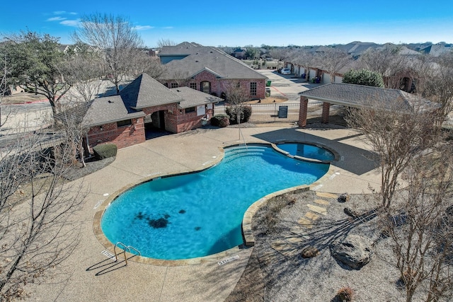 view of pool featuring a patio area, fence, and a pool with connected hot tub