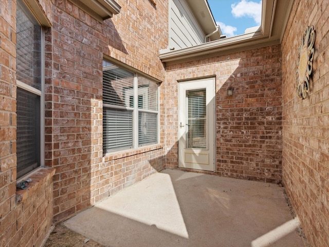 entrance to property with brick siding and a patio area