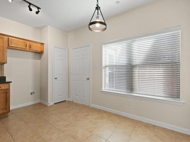 unfurnished dining area featuring light tile patterned floors and baseboards