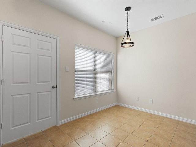 empty room featuring light tile patterned floors, visible vents, and baseboards