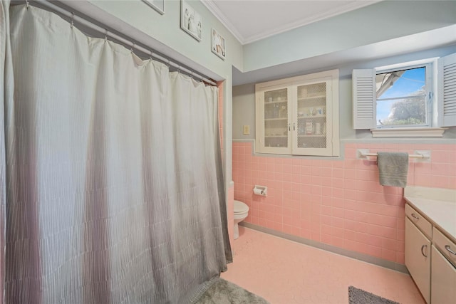 full bathroom featuring vanity, a wainscoted wall, crown molding, tile walls, and toilet