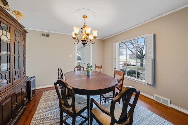 dining room with dark wood finished floors, visible vents, and a notable chandelier