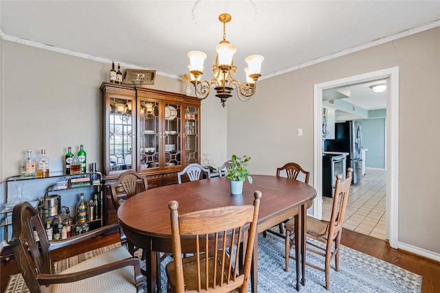 dining space with a chandelier, baseboards, wood finished floors, and ornamental molding