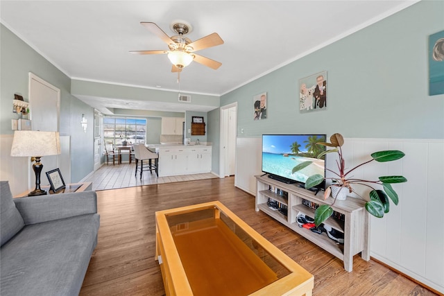 living area featuring visible vents, ornamental molding, and wood finished floors