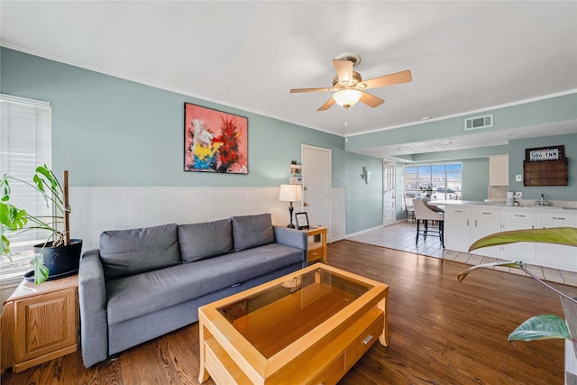 living room with visible vents, crown molding, ceiling fan, and wood finished floors