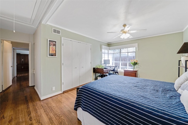 bedroom with visible vents, baseboards, attic access, wood finished floors, and a closet