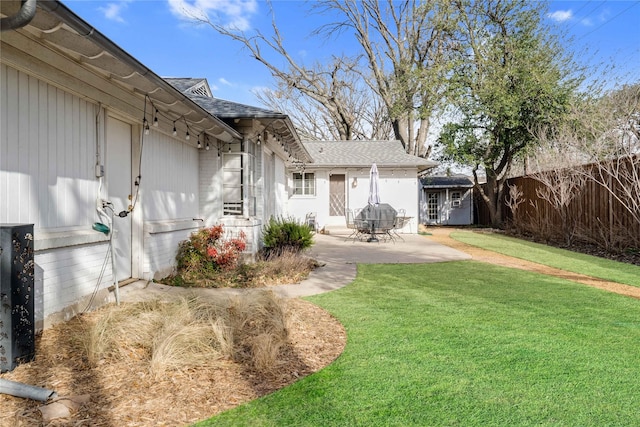 exterior space with a patio area, a shingled roof, a yard, and fence