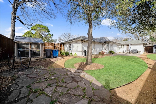 view of side of property featuring a patio, a fenced backyard, a yard, a sunroom, and metal roof