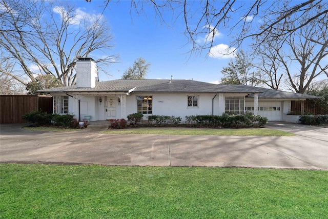 ranch-style home featuring fence, concrete driveway, a front yard, a chimney, and an attached garage