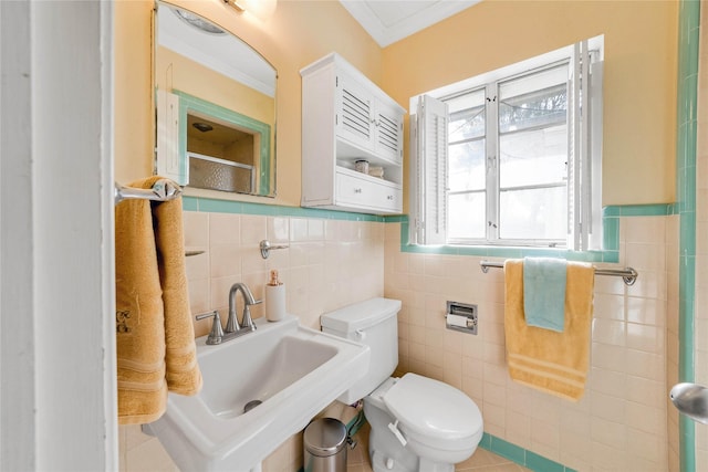 bathroom featuring a sink, toilet, tile walls, and crown molding