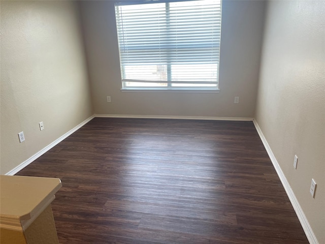 spare room featuring dark wood-style floors and baseboards