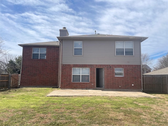 back of property featuring brick siding, a chimney, a fenced backyard, a yard, and a patio