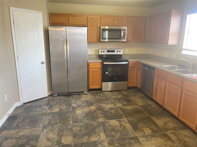 kitchen with light countertops, stone finish flooring, appliances with stainless steel finishes, and a sink