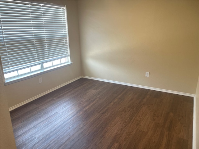 spare room with dark wood finished floors and baseboards