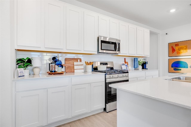 kitchen featuring light countertops, light wood finished floors, backsplash, and stainless steel appliances