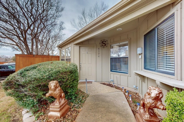 property entrance with board and batten siding and fence