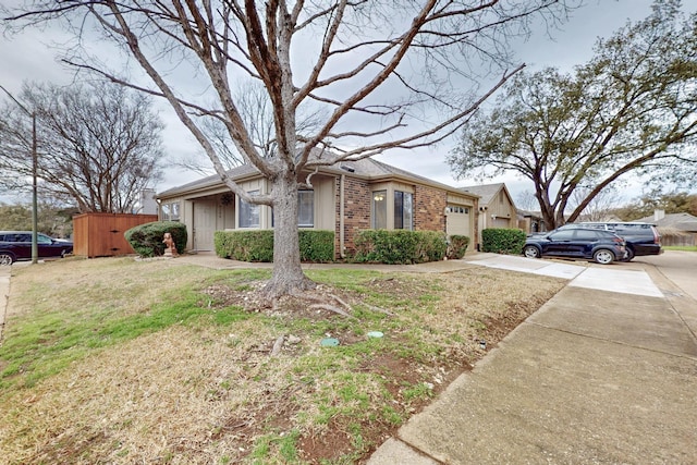 view of front of house featuring driveway, brick siding, an attached garage, and a front lawn