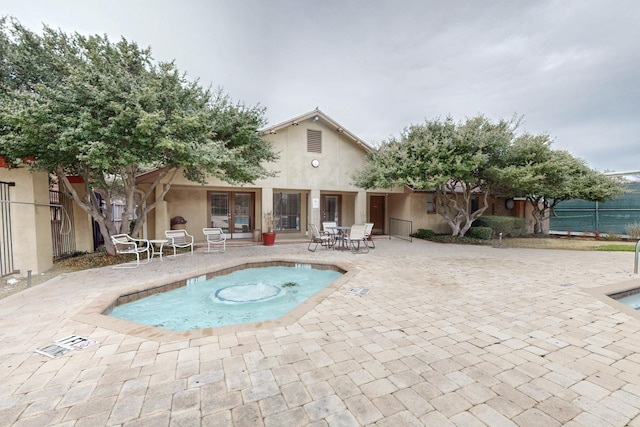 rear view of property featuring stucco siding, a patio, and fence