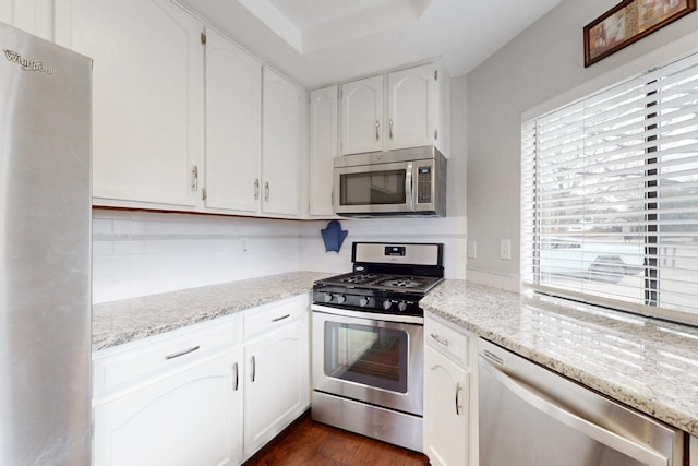 kitchen featuring dark wood-type flooring, light stone countertops, decorative backsplash, white cabinets, and stainless steel appliances