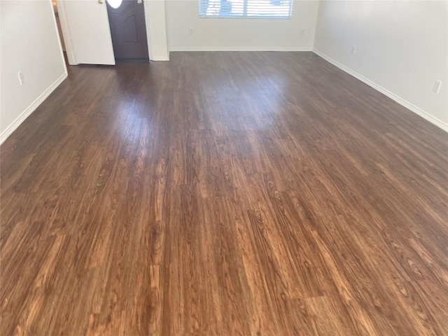 unfurnished room featuring baseboards and dark wood finished floors