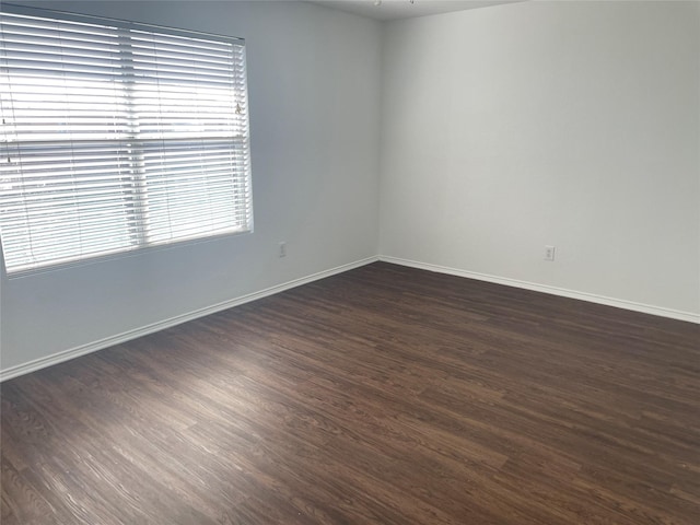 unfurnished room with baseboards and dark wood-style flooring