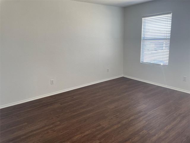 empty room featuring dark wood-style floors and baseboards