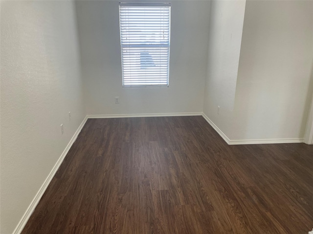 spare room with dark wood-style floors and baseboards