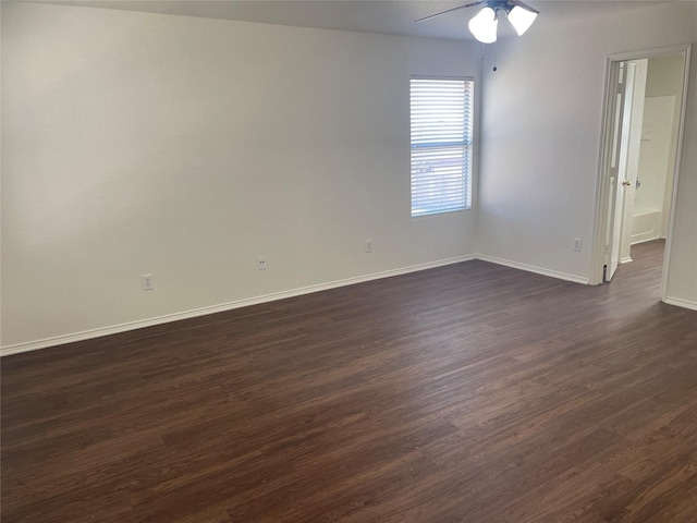 empty room with a ceiling fan, dark wood-style floors, and baseboards