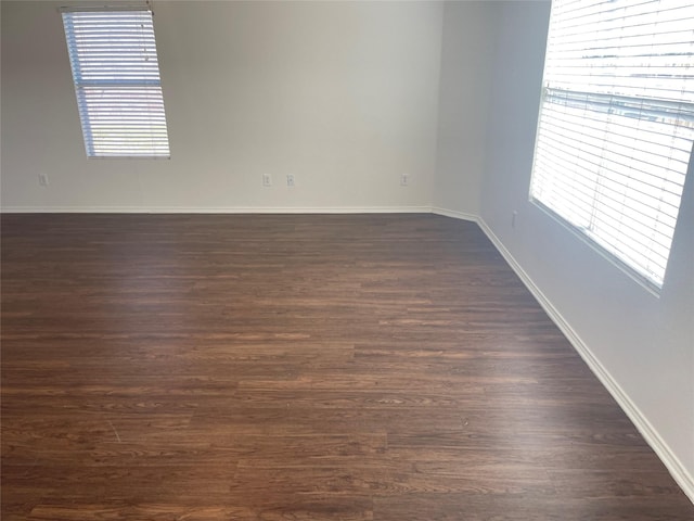 spare room with dark wood-style floors and baseboards