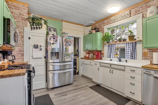 kitchen featuring brick wall, a sink, butcher block countertops, wood ceiling, and appliances with stainless steel finishes