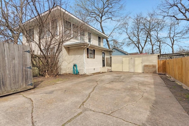 view of side of home with a patio area, an outdoor structure, fence private yard, and stucco siding