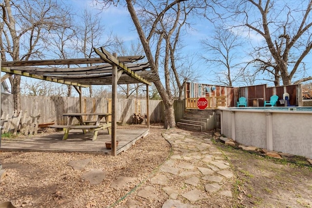 view of yard featuring an outdoor pool, a wooden deck, a fenced backyard, and a pergola