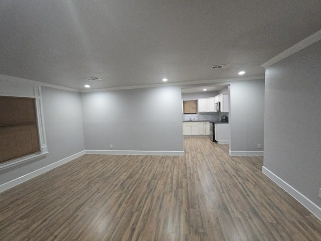 unfurnished living room featuring wood finished floors, visible vents, baseboards, recessed lighting, and ornamental molding