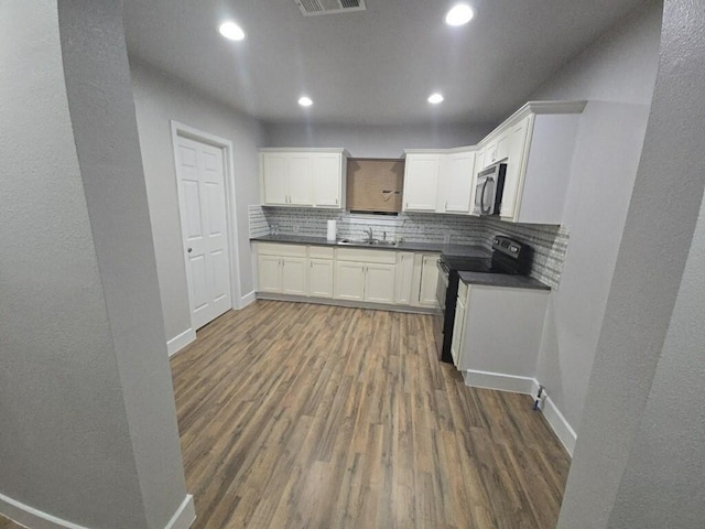 kitchen featuring black / electric stove, dark wood-style floors, dark countertops, decorative backsplash, and stainless steel microwave