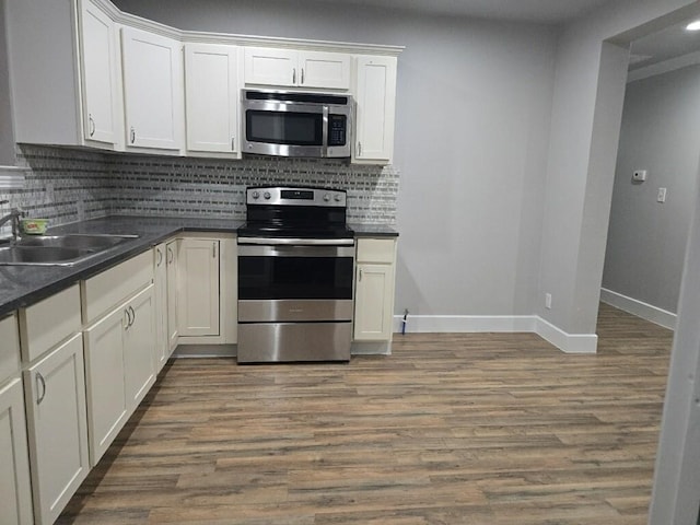 kitchen with dark countertops, wood finished floors, appliances with stainless steel finishes, and a sink