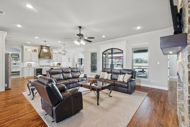 living room featuring recessed lighting, wood finished floors, arched walkways, and ornamental molding