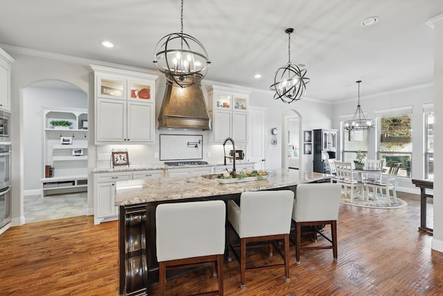 kitchen featuring arched walkways, a notable chandelier, wood finished floors, and tasteful backsplash