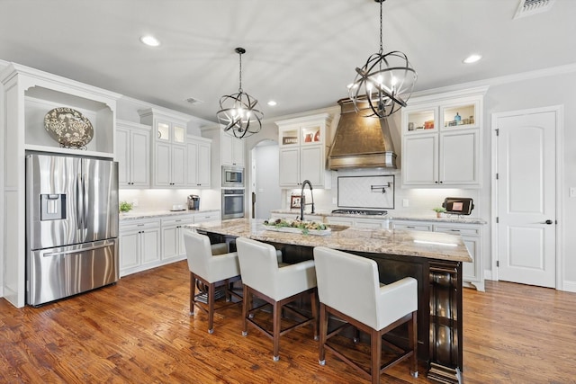 kitchen with dark wood-style floors, visible vents, premium range hood, arched walkways, and appliances with stainless steel finishes