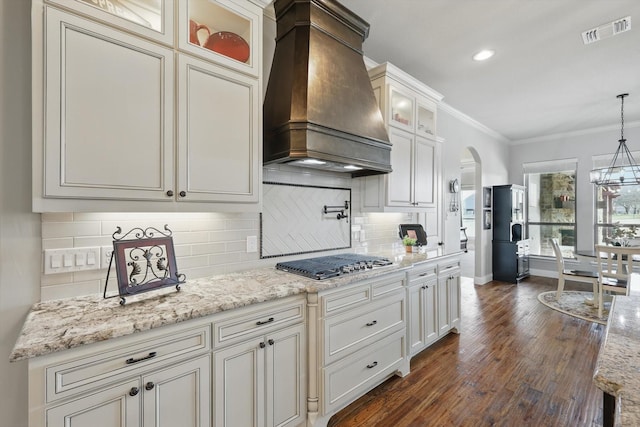 kitchen with visible vents, premium range hood, stainless steel gas cooktop, arched walkways, and crown molding