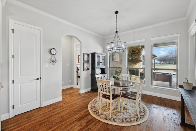 dining space with baseboards, arched walkways, dark wood-style flooring, and ornamental molding