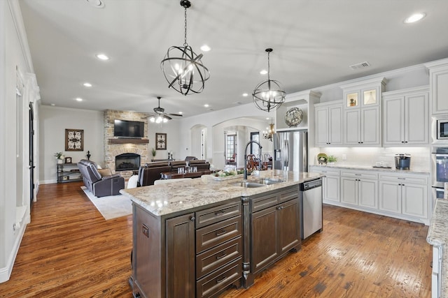 kitchen with visible vents, a sink, stainless steel appliances, arched walkways, and a fireplace