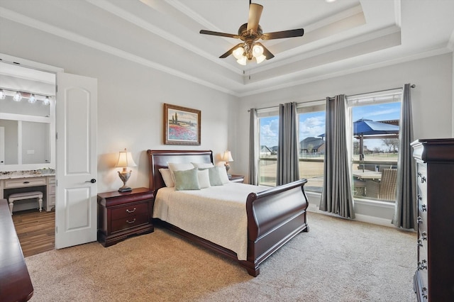 bedroom with light carpet, a ceiling fan, crown molding, and a tray ceiling