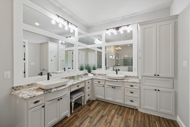 bathroom with double vanity, a stall shower, wood finished floors, and a sink