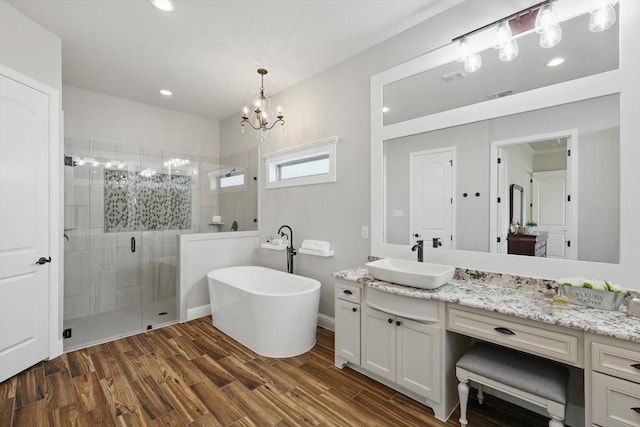 bathroom with a freestanding tub, visible vents, a stall shower, wood finished floors, and vanity