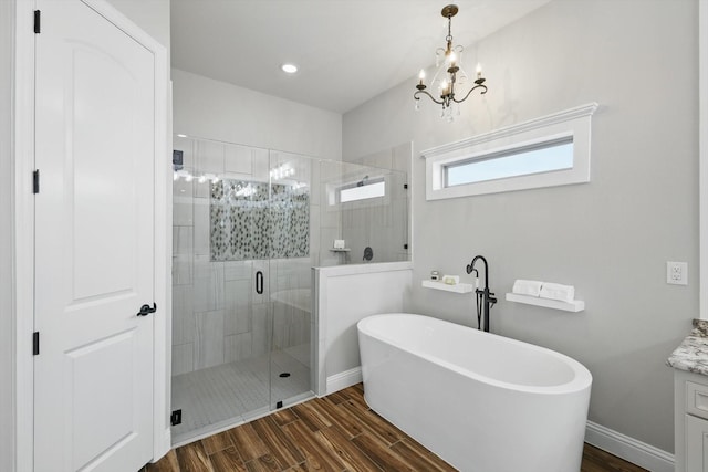 bathroom with a shower stall, baseboards, wood finished floors, a soaking tub, and vanity