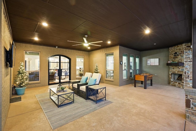 living room featuring concrete floors, wood ceiling, an outdoor stone fireplace, arched walkways, and a ceiling fan